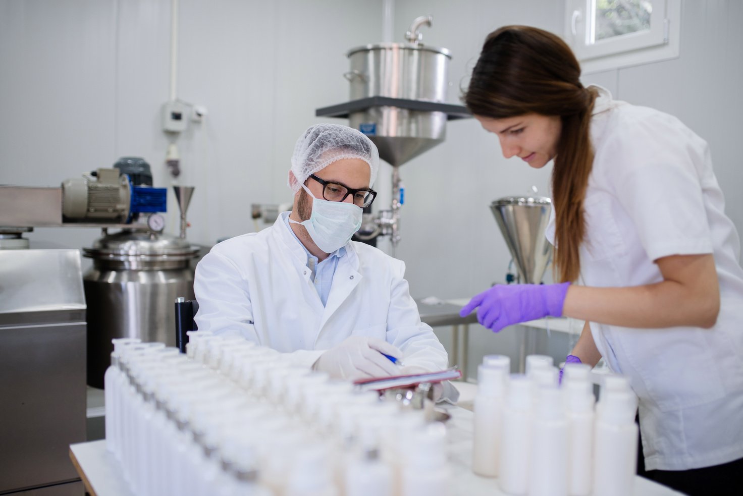 Technologist and his assistant testing quality of cosmetic products.